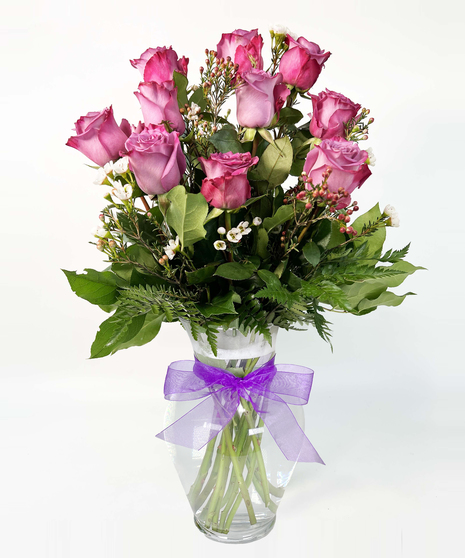 Bouquet of lavender roses with seeded eucalyptus in a clear glass vase. 