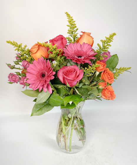 Vibrant orange & pink roses in a clear glass vase.